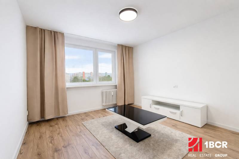 Wohnzimmer mit Holzboden, Couchtisch und weißem Schrank in einer Zweizimmerwohnung.