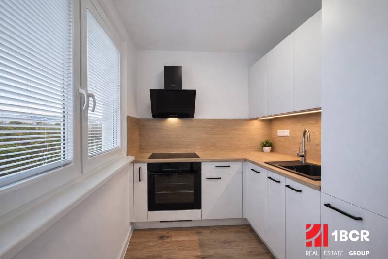 Die Küche einer 2-Zimmer-Wohnung mit einem Boden in Holzoptik und weißen Schränken.