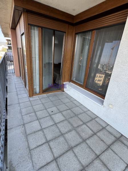 Balkon mit Fliesen und Holzdekor, Teil einer 2-Zimmer-Wohnung, mit Geländer und Aussicht.