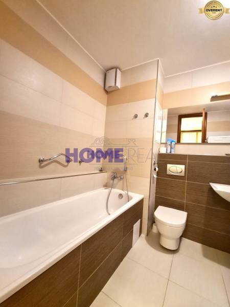 Badezimmer mit Badewanne, Urinal und Waschbecken in einer 2-Zimmer-Wohnung.