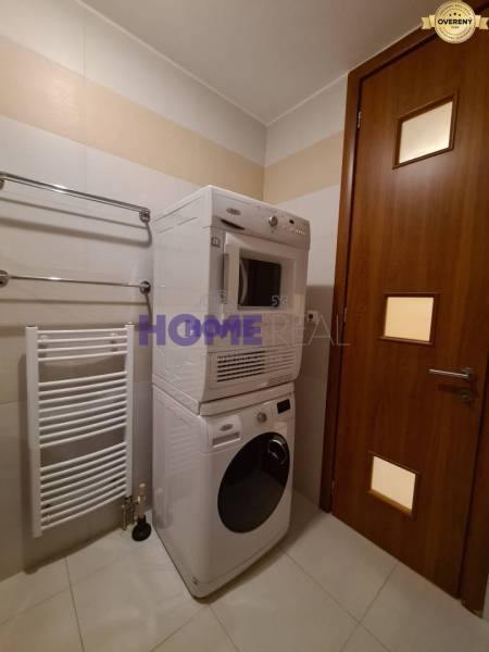 Badezimmer in einer 2-Zimmer-Wohnung mit Waschmaschine und Trockner, weißem Heizkörper an der Wand.