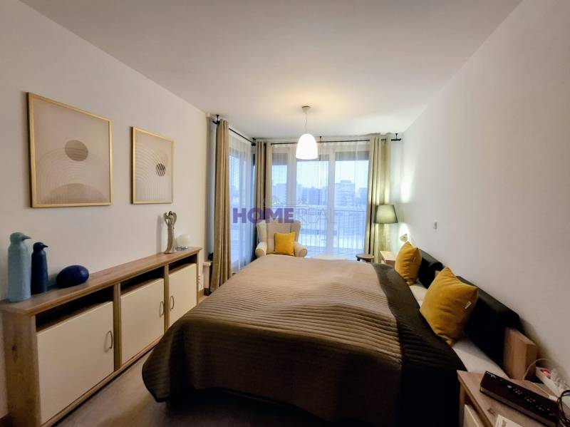 Schlafzimmer mit Bett, dekorativen Kissen und Kommode in einer Zweizimmerwohnung.