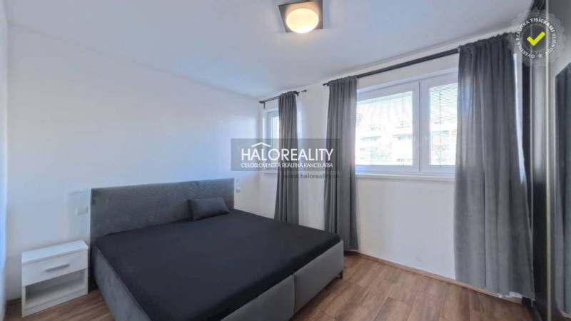 Schlafzimmer mit Bett in einer 2-Zimmer-Wohnung, Fenster mit Rollläden, Boden mit Holzdekor.