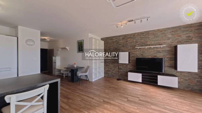 Wohnzimmer in einer 2-Zimmer-Wohnung mit Holzboden und Steinverkleidung.