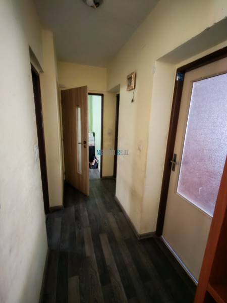 Der Flur in einem Einfamilienhaus mit einem Boden in Holzoptik, hellen Wänden und Glastüren.