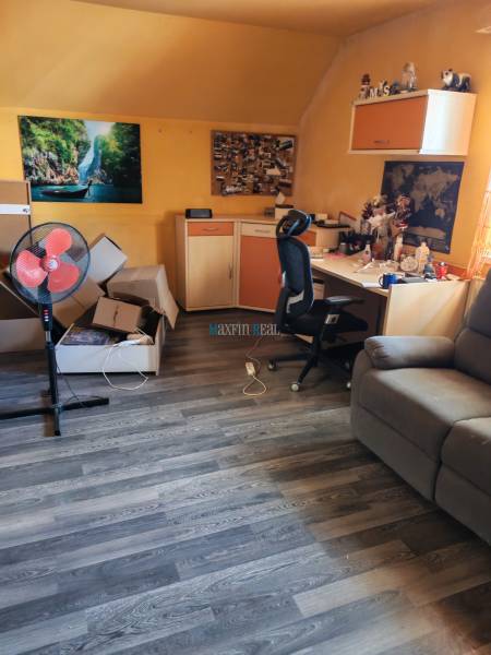 Ein Zimmer in einem Einfamilienhaus mit einem Schreibtisch, einem Stuhl und einem Boden mit Holzdekor.