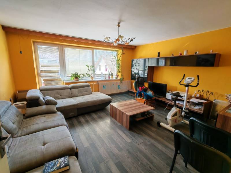 Wohnzimmer eines Einfamilienhauses mit einem Boden in Holzoptik und gelben Wänden.