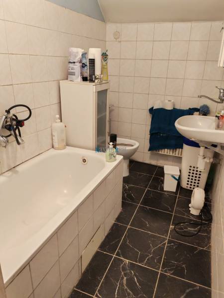 Ein Badezimmer in einem Einfamilienhaus mit einer Badewanne, einem Waschbecken und Fliesen mit dunklem Muster.