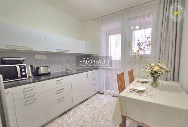 Küche in einer 4-Zimmer-Wohnung mit Tisch, Stühlen und Geräten.