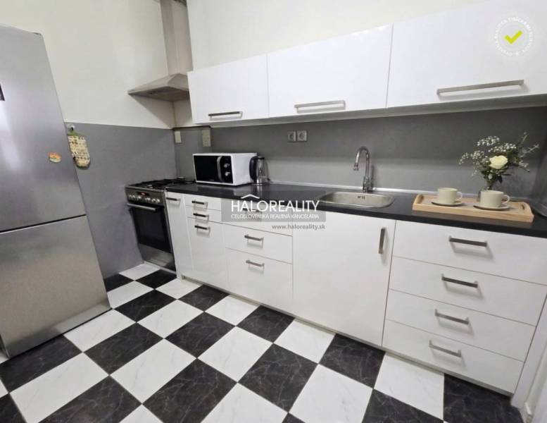 Küche in einer 4-Zimmer-Wohnung mit schwarz-weißem Fliesenboden und weißen Schränken.
