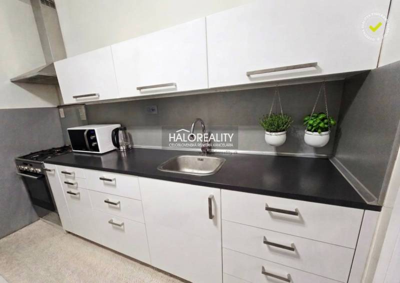 Küche mit Geräten und Kräutern in einer 4-Zimmer-Wohnung, weiße Einheit, graue Arbeitsplatte.
