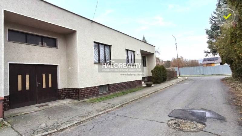 Ein Einfamilienhaus in der Stadt Poltár mit Flachdach und einer Garage an der Straße.