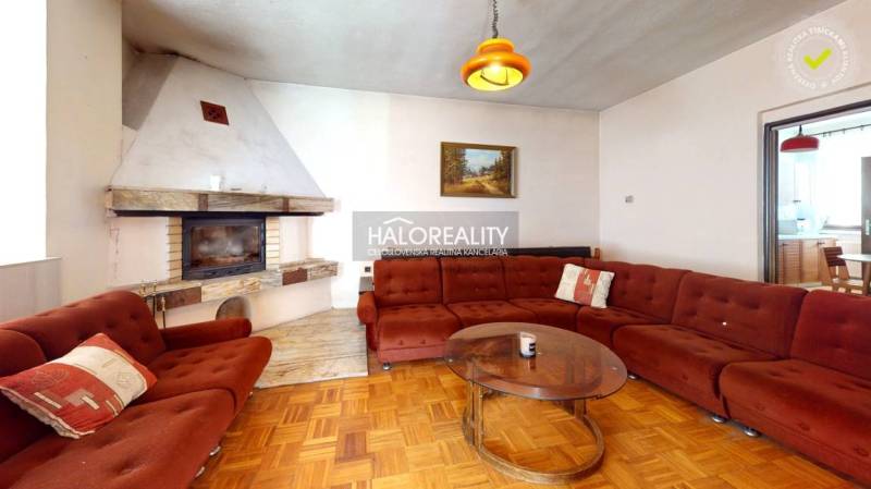 Wohnzimmer mit Kamin und Sofa in einem Einfamilienhaus, mit Holzboden.