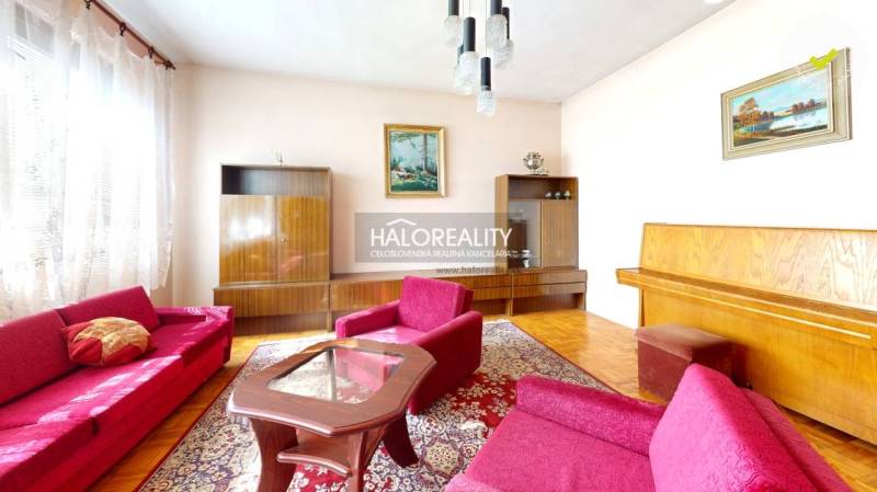 Wohnzimmer in einem Einfamilienhaus mit Teppichmuster und Holzboden.