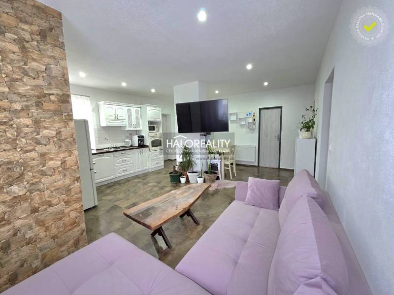 Wohnzimmer eines Einfamilienhauses mit Steinverkleidung und Küchenzeile.