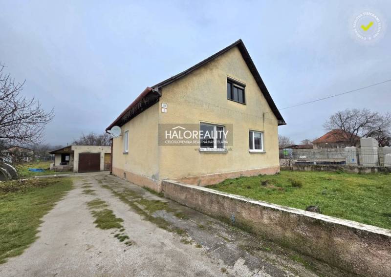 Ein Einfamilienhaus in Čereňany mit Garage, grünem Rasen und Zufahrtsweg.