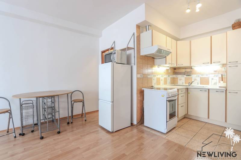 Küche in einer 2-Zimmer-Wohnung mit Holzboden, Esstisch und Kühlschrank.