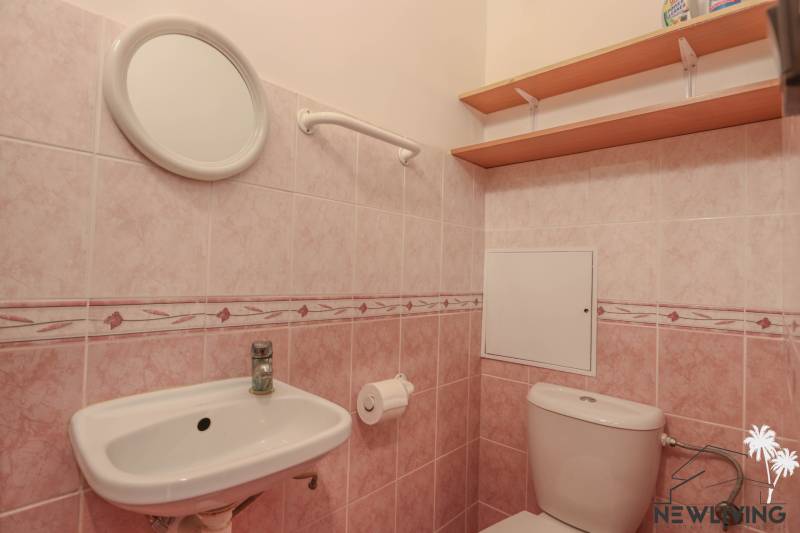 Badezimmer mit rosa Fliesen und Sanitäranlagen in einer 2-Zimmer-Wohnung.