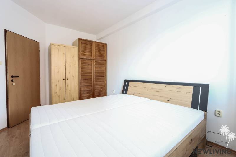 Schlafzimmer in einer 2-Zimmer-Wohnung mit Bett und Holzschränken, Boden mit Holzdekor.