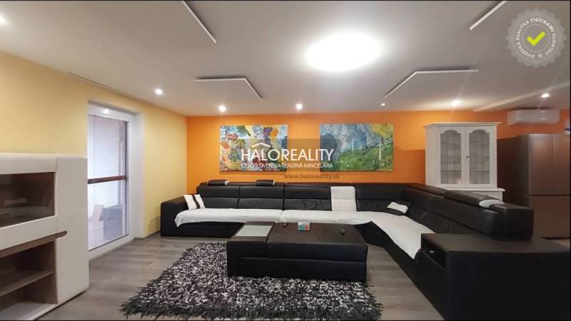 Wohnzimmer in einem Einfamilienhaus mit geräumigem Sofa und Zeichnungen an der orangefarbenen Wand.