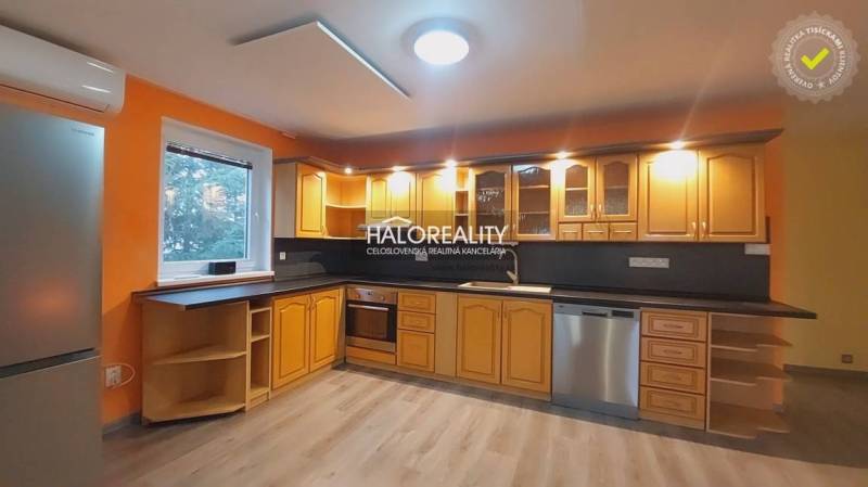 Küche mit orangefarbenen Wänden, Holzschränken und einem Boden mit Holzdekor in einem Einfamilienhaus.