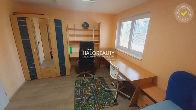 Ein Zimmer in einem Einfamilienhaus mit einem Boden in Holzoptik, einem Schrank und einem Schreibtisch.