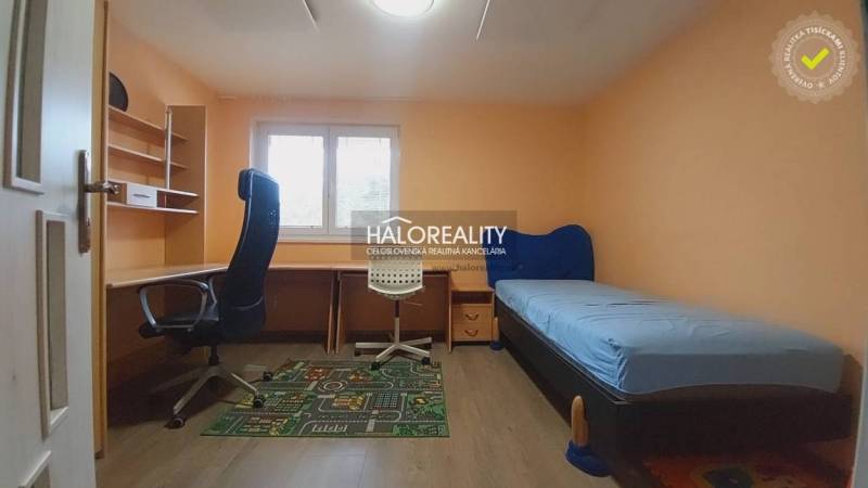 Kinderzimmer in einem Einfamilienhaus mit Tisch, Bett und Bürostuhl.
