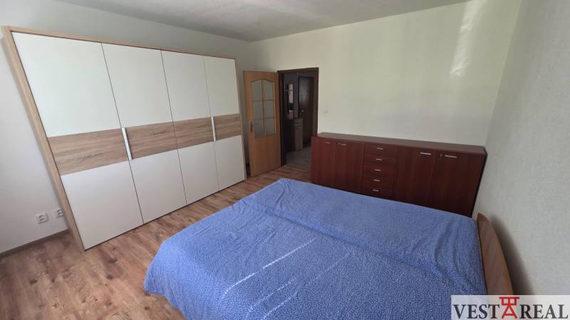 Schlafzimmer in einer Einzimmerwohnung mit Holzboden und praktischem Möbel.