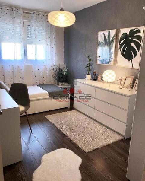 Ein Zimmer in einem Einfamilienhaus mit einem Boden in Holzoptik, Kunstgemälden und dekorativen Blumen.