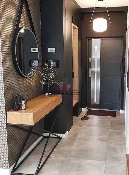 Eingangsbereich mit rundem Spiegel, Holzkonsolentisch und dekorativen Elementen in einem Einfamilienhaus.