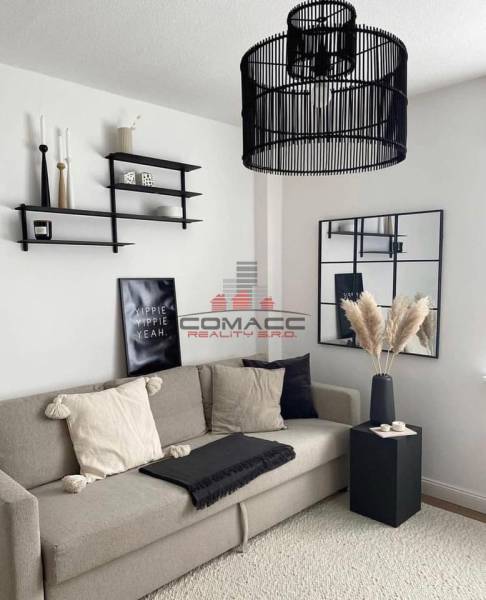 Wohnzimmer in einem Einfamilienhaus mit bequemer Couch, dekorativen Regalen und modernem Kronleuchter.