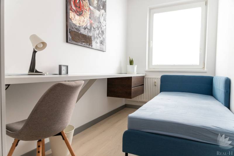 Arbeitsbereich in einer 4-Zimmer-Wohnung mit Sofa und Tisch auf hellem Boden.