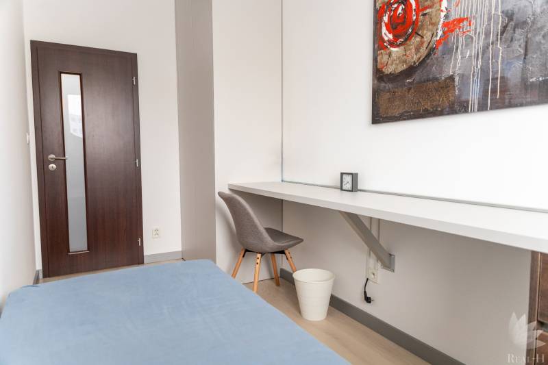Ein Zimmer in einer 4-Zimmer-Wohnung mit einem Boden in Holzoptik, einem Tisch und einem Sessel.