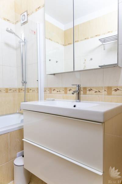 Badezimmer mit Duschkabine, Spiegelschrank und Waschbecken in einer 4-Zimmer-Wohnung.