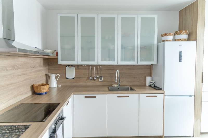 Küche in einer 4-Zimmer-Wohnung mit Holzboden und weißen Schränken.
