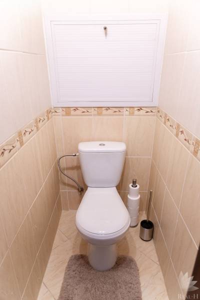 Toilette mit beigen Fliesen und Teppich in einer 4-Zimmer-Wohnung.