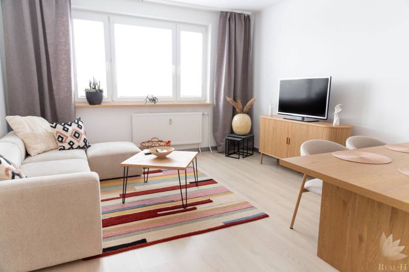 Wohnzimmer in einer 4-Zimmer-Wohnung mit Holzboden, Sofa und Fernseher.