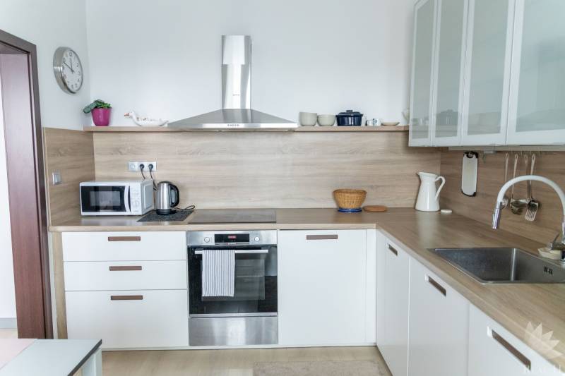 Küche mit eingebauten Geräten in einer 4-Zimmer-Wohnung, Boden mit Holzdekor, helle Küchenzeile.