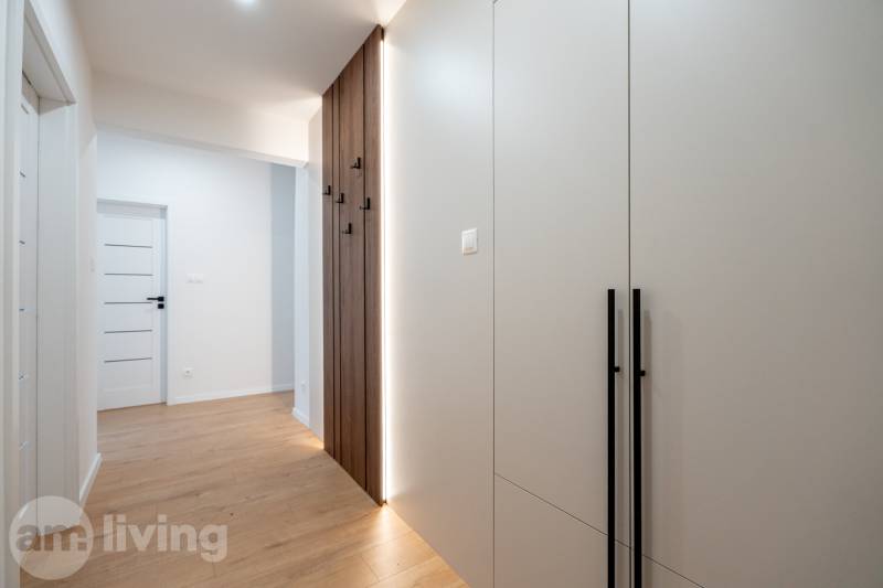 Der Flur in einer 3-Zimmer-Wohnung mit einer hellen Wand und einem Boden in Holzoptik.