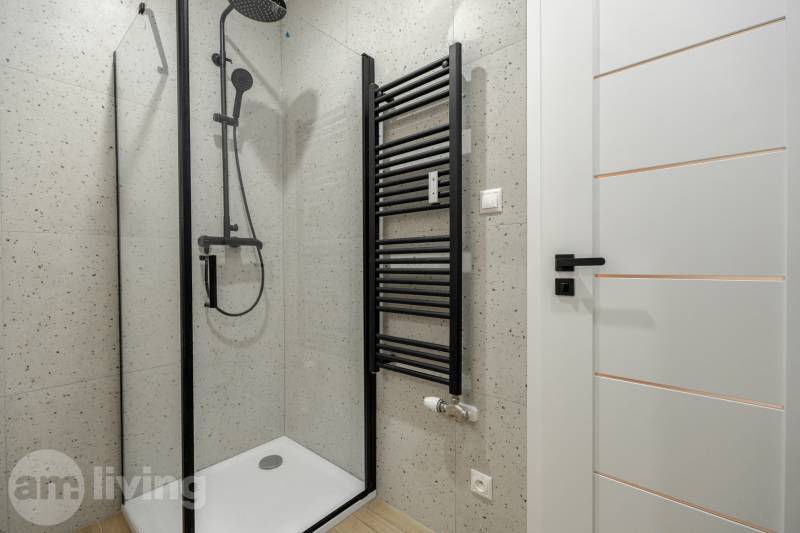 Duschkabine mit schwarzem Duschset und Heizkörper im 3-Zimmer-Wohnung.