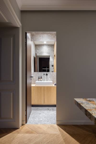 Badezimmer mit grauen Fliesen und Waschbecken in einer 4-Zimmer-Wohnung, Boden mit Holzdekor.