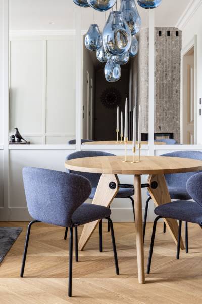 Ein runder Tisch mit blauen Stühlen und hängenden Leuchten in einer 4-Zimmer-Wohnung mit Holzboden.