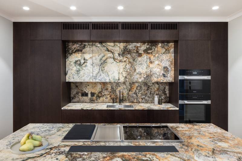 Eine Küche mit markanten Marmoroberflächen und dunkler Holzverkleidung in einer Vierzimmerwohnung.