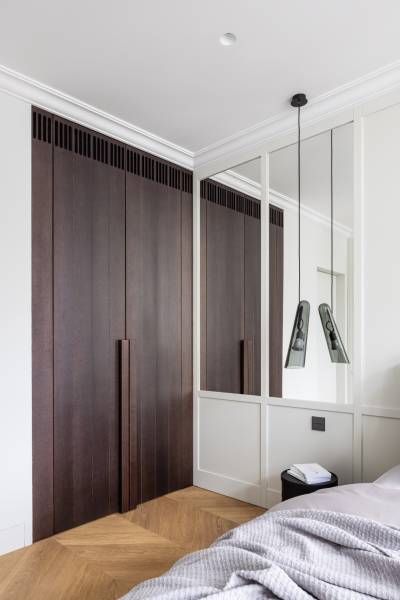 Schlafzimmer in einer 4-Zimmer-Wohnung mit Holzboden und einem Kleiderschrank aus dunklem Holz.