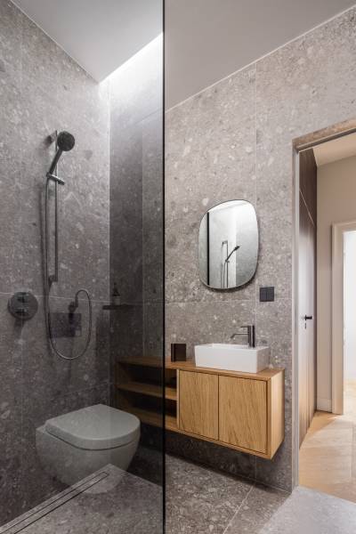 Badezimmer mit Dusche, Steinwänden und Waschbecken in einer 4-Zimmer-Wohnung.