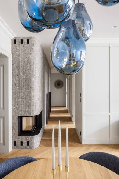 Elegantes Interieur in einer 4-Zimmer-Wohnung mit blauen Kronleuchtern und einem Boden in Holzoptik.