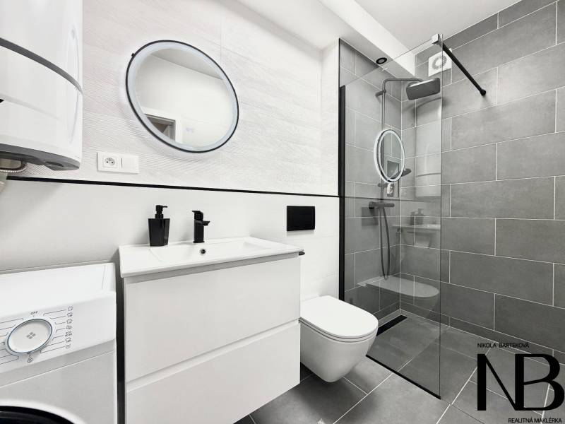 Badezimmer in einer Einzimmerwohnung mit modernen grauen Fliesen und einer Duschkabine aus Glas.