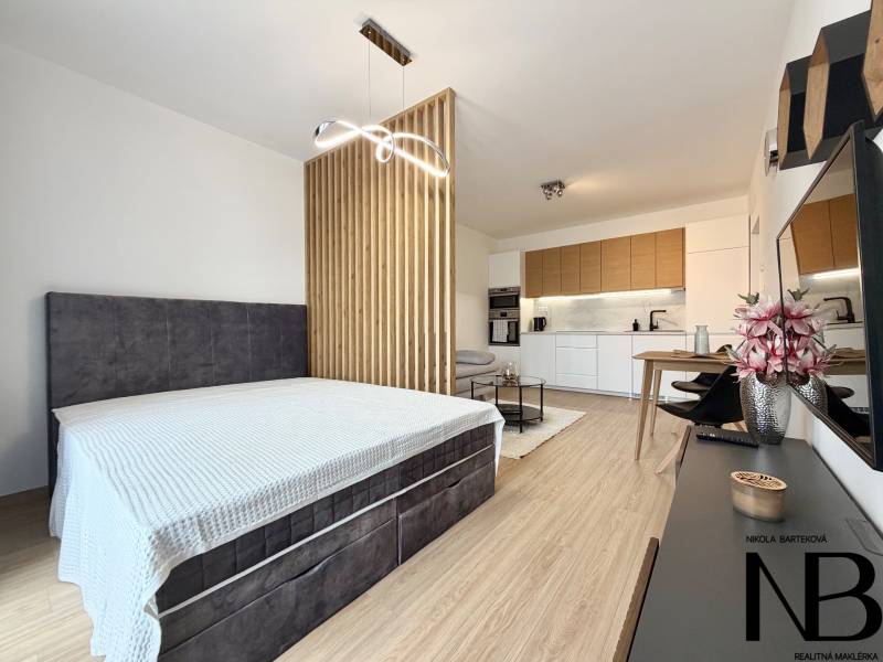 1-Zimmer-Wohnung mit Kochnische, Bett und Boden in Holzoptik.