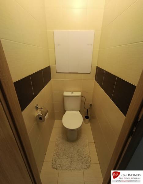 Badezimmer in einer 4-Zimmer-Wohnung mit Toilette und Fliesen, ergänzt durch einen hellen Teppich.