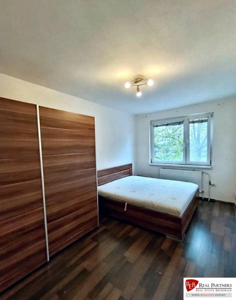 Schlafzimmer mit Schrank, Bett und Boden in Holzoptik in einer 4-Zimmer-Wohnung.